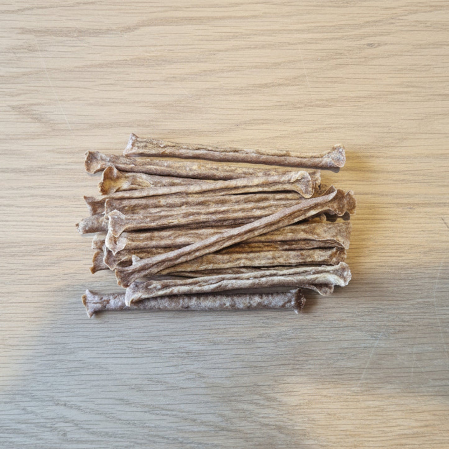 Stack of 15 Ostrich muscle meat sticks on a wooden surface