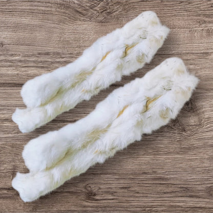 Two Hilltop Pet Food Furry Rabbit Skins (Pelts) with light brown spots lie side by side on a wooden surface.