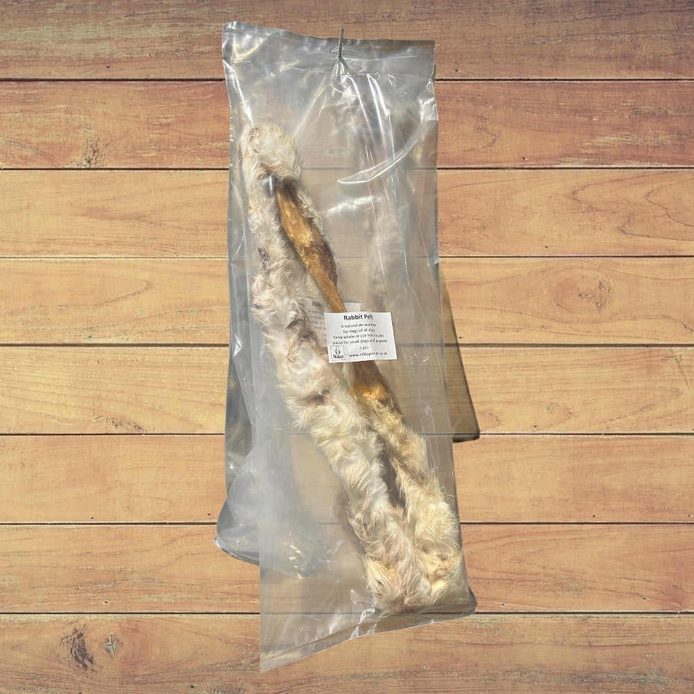 A sealed bag of Hilltop Pet Food Furry Rabbit Skin (Pelt) on a wooden surface.