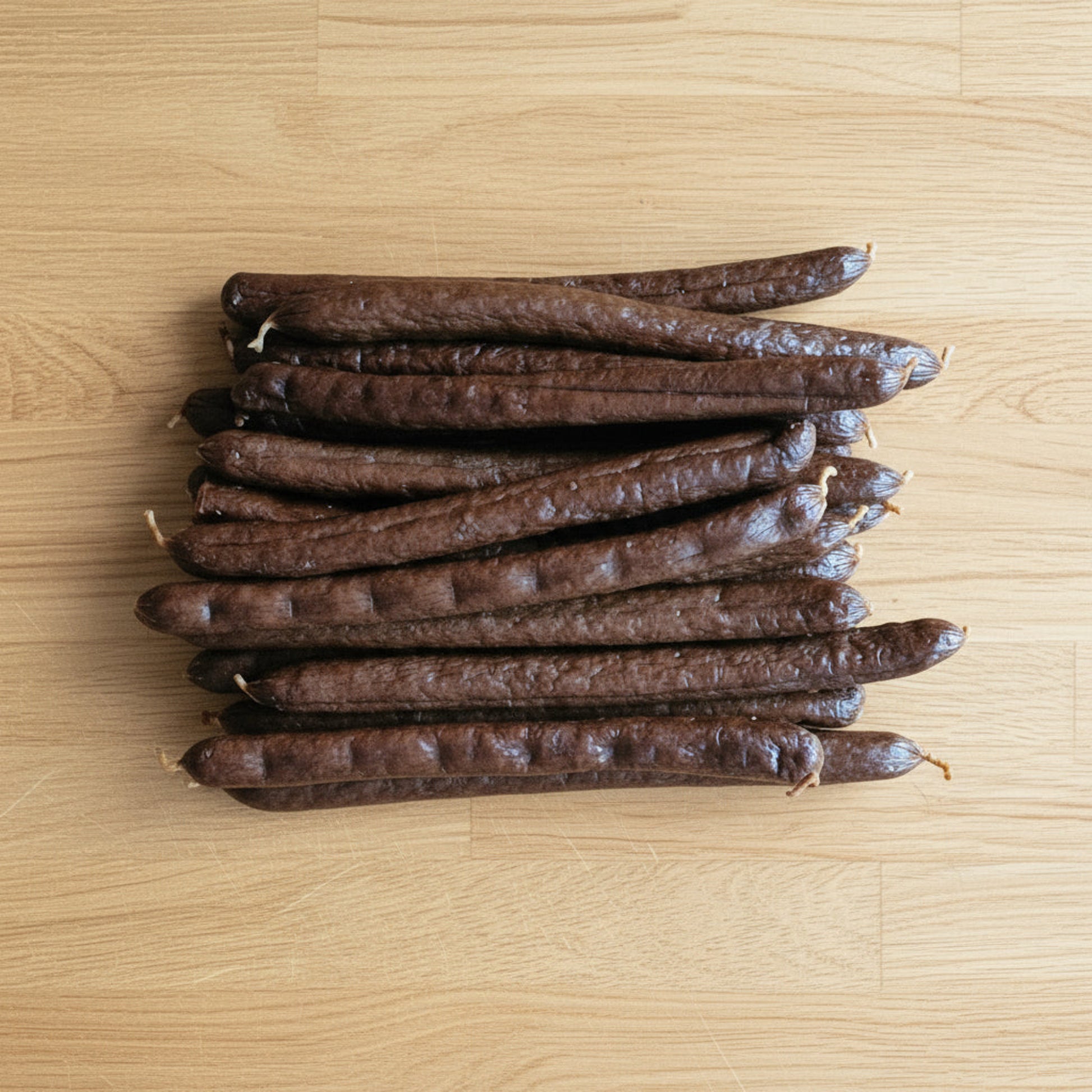Stack of long meaty sausages, chicken, pumpkin & turmeric on a wooden surface
