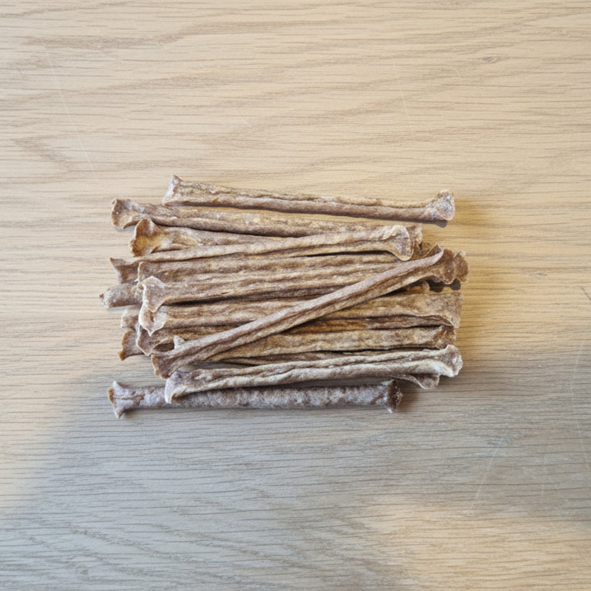 Stack of 15 Ostrich muscle meat sticks on a wooden surface